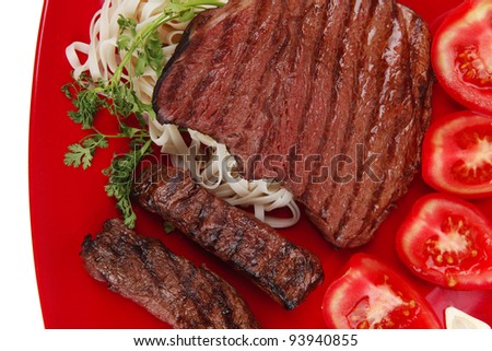 italian food : pasta with tomato and grilled sirloin beef on red plate isolated over white background