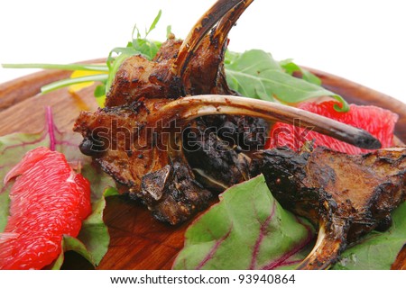 main portion : grilled ribs on wooden plate isolated over white background with salad leaves and red grapefruit
