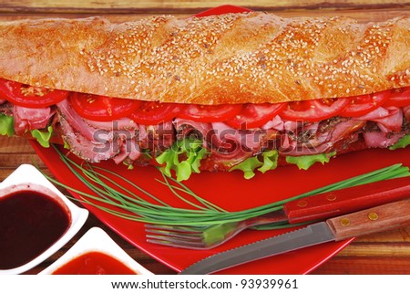 french sandwich on red plate : long baguette with smoked chicken sausage with sauces over wood