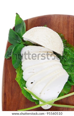 mediterranean dairy  : fresh raw white soft greek feta cheese round and slices on wooden plate isolated over white background