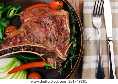 meat food : grilled beef spare rib on dark dish with thyme pepper and tomato on wooden table