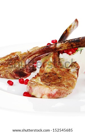 meat food: ribs on white plate with rice garnish and tomatoes over white background