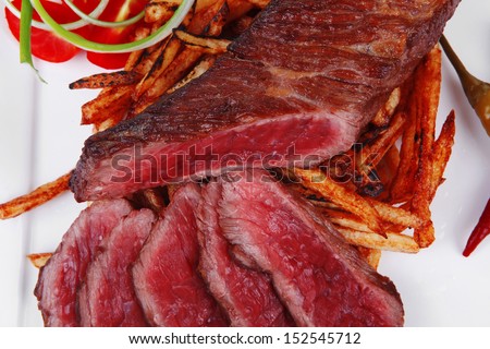 meat food : rare beef on potato chips with pepper and tomatoes over plate isolated on white background