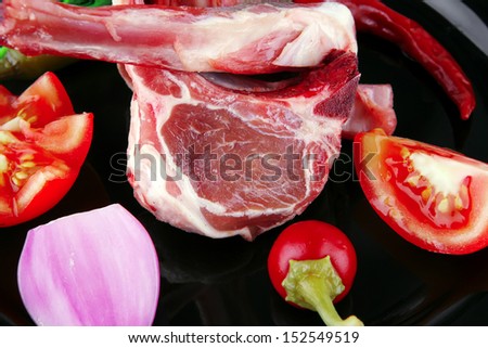 raw lamb chops on plate with vegetables