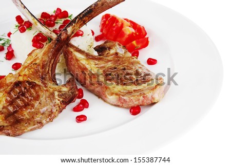 meat food: ribs on white plate with rice garnish and tomatoes over white background