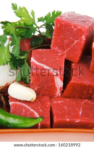 low fat raw fresh beef meat slices in a ceramic dish with garlic and peppers isolated over white background