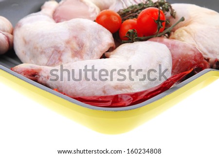 raw chicken legs with tomatoes and thyme on yellow ceramic pan ready to cooking isolated on white background health care low fat meat