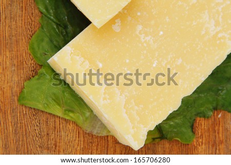 gold swiss cheese on wooden platter with olives and tomato isolated over white background