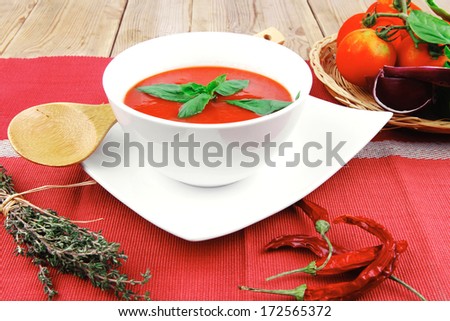 Cold Fresh Diet Tomato Soup With Basil Thyme And Dry Pepper In Big Bowl Over Red Mat On Wood Table Ready To Eat