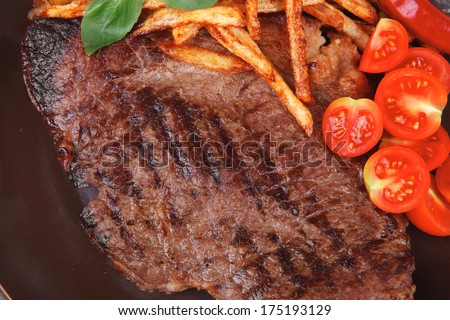 main course : grill beef steak with potato chips and fresh cherry tomato , red hot chili peppers on plate isolated on white background