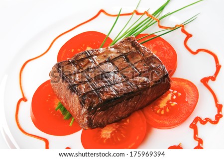 grilled beef meat entrecote fillet served with tomatoes and green chives  on white china plate isolated over white background