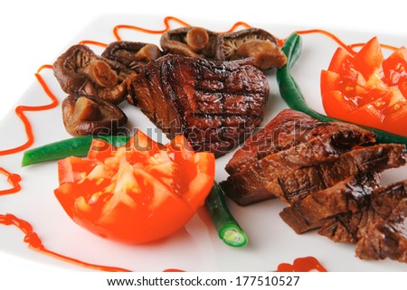 served grilled beef fillet mignon entrecote on a white plate with mushrooms and tomatoes on plate isolated on white background