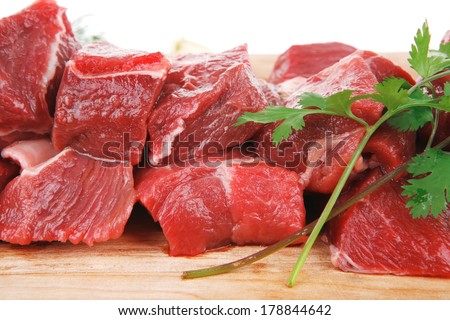 fresh raw beef meat slices over a wooden board with dill , green  and red hot peppers isolated over white background