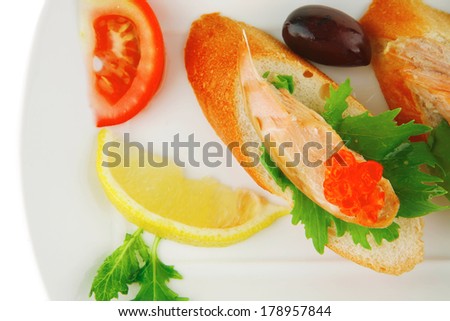 healthy appetizer : sandwich with sea salmon and red caviar, olives, tomato and lemon on white china plate isolated over white background