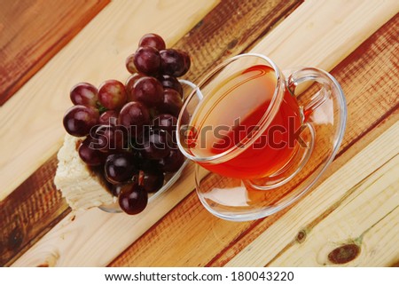 cream cheese schnitt layer cake with tea and red fresh sweet grapes on wood background