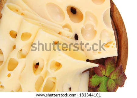 gold swiss cheese sliced on wooden platter with olives and tomato isolated over white background