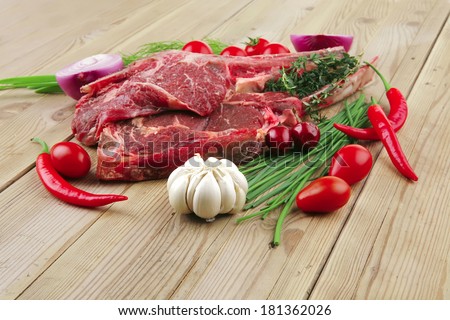 raw meat : boned fresh lamb ribs served with thyme , red chili pepper , cherry tomato , and green onion over wooden table