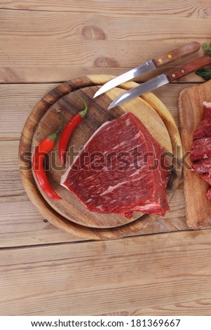 fresh raw beef meat steak and chunk with red hot pepper and dill on wooden cut plates over table
