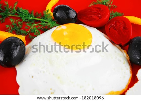 fried scrambled eggs eye with white goat feta cheese on red plate isolated over white background with black olives and vegetables