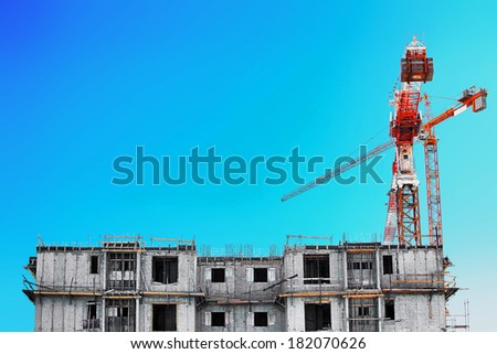 a large lifting crane at the building site near a building under construction