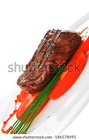 grilled beef meat entrecote fillet served with tomatoes and green chives  on white china plate isolated over white background