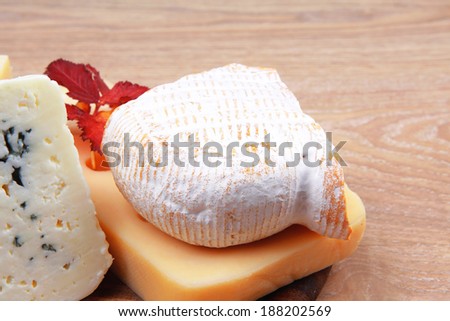 various types of cheese on wooden platter over wooden table