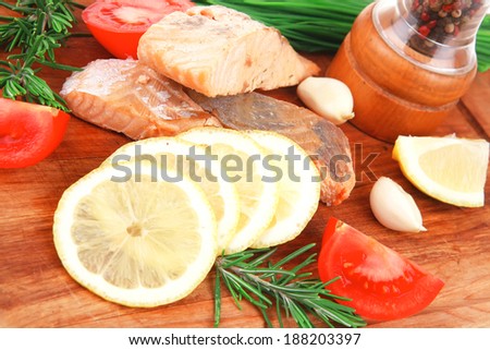 sea food : roasted pink salmon fillet with chinese onion, cherry tomatoes pieces, pepper grinder, rosemary twigs and lemon on wooden board isolated over white background