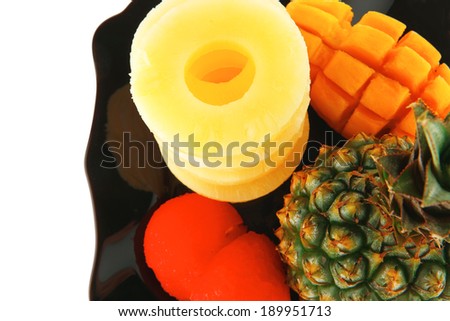 raw pineapple on black plate isolated over white background