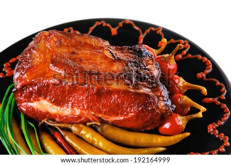roast red beef meat bbq bloc served on black plate  with green chives adn red hot pepper on black plate isolated over white background