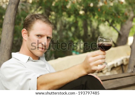young happy white caucasian man taste and enjoy red wine outdoor in in countryside . classic style fashion.