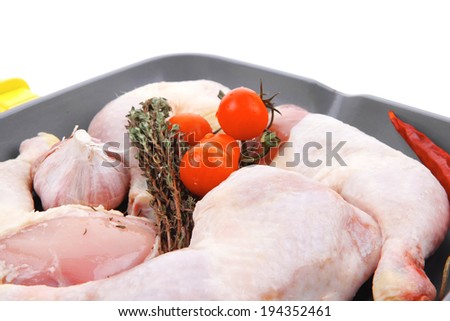 raw chicken legs with tomatoes and thyme on yellow ceramic pan ready to cooking isolated on white background