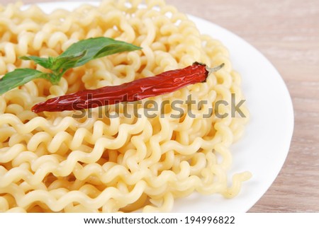 italian food : boiled pasta with basil and red pepper on white dish over wooden table