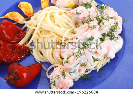 fresh rose wild salmon baked in cream cheese sauce with italian pasta and red hot pepper on blue plate isolated over white background