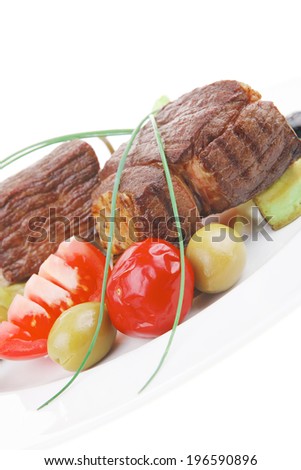 savory food : roast beef garnished with baked apples , green and black olives on white plate isolated over white background