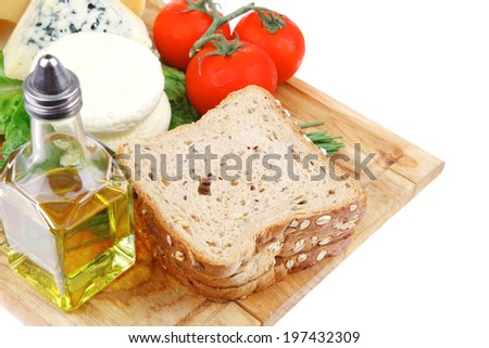 delicatessen cheeses on wooden board with vegetables olive oil and bread isolated over white background