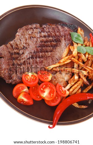 meat food : big grill beef steak on dark plate with red hot chili pepper and raw cherry tomato isolated on white background