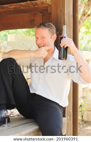 young happy white Caucasian man taste and enjoy red wine outdoor in in countryside . classic style fashion.