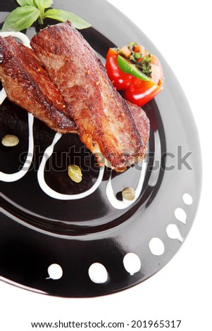 fresh red beef meat steak barbecue garnished vegetable salad sweet potato and basil on black plate isolated over white background
