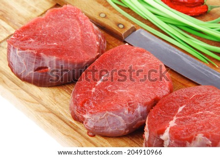 raw fillet chops : fresh beef meat with thyme and red hot dry pepper on wooden plate . isolated over white background