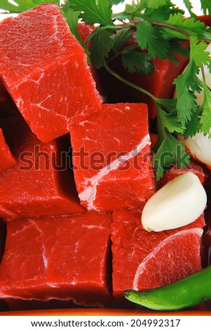 raw fresh beef meat slices in a ceramic dish with garlic and peppers isolated over white background
