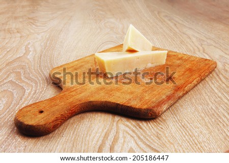 two fresh triangle french delicacy parmesan cheese pieces on wooden cut board over table