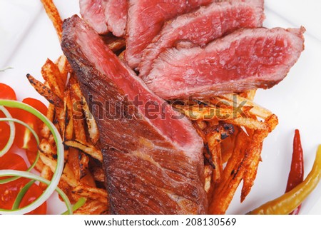 meat food : rare beef on potato chips with pepper and tomatoes over plate isolated on white background