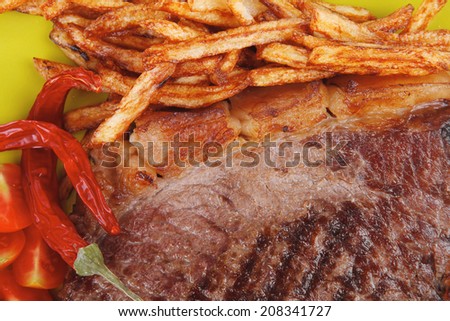 main course : grill beef steak with potato chips and fresh cherry tomato , dry red hot chili peppers on green plate isolated on white background