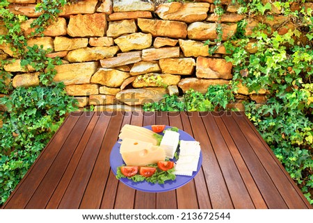 savory set of cheese greek goat feta yellow fromage french on blue plate over wooden table at outdoor garden near old ancient wall