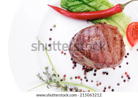 grilled beef fillet pieces on noodles , red hot chili pepper with tomato and green salad leaf on white plate isolated over white background