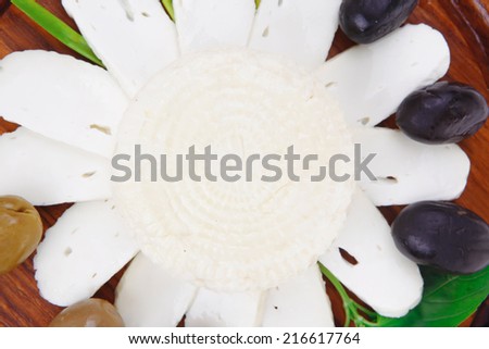 dairy products : feta white cheese sliced on cut board with olives and basil leaves isolated over white background
