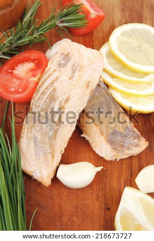 sea food : roasted pink salmon fillet with chinese onion, cherry tomatoes pieces , rosemary twigs and lemon on wooden board isolated over white background