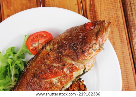 savory on plate : roast golden fish served on fish plate with lemon tomatoes and spices