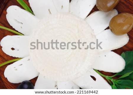 diet products : salted greek feta white cheese with olives and basil leaves sliced on wood isolated over white background
