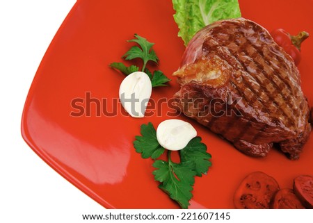 meat food : roast beef garnished with green lettuce and red chili hot pepper on red plate isolated over white background